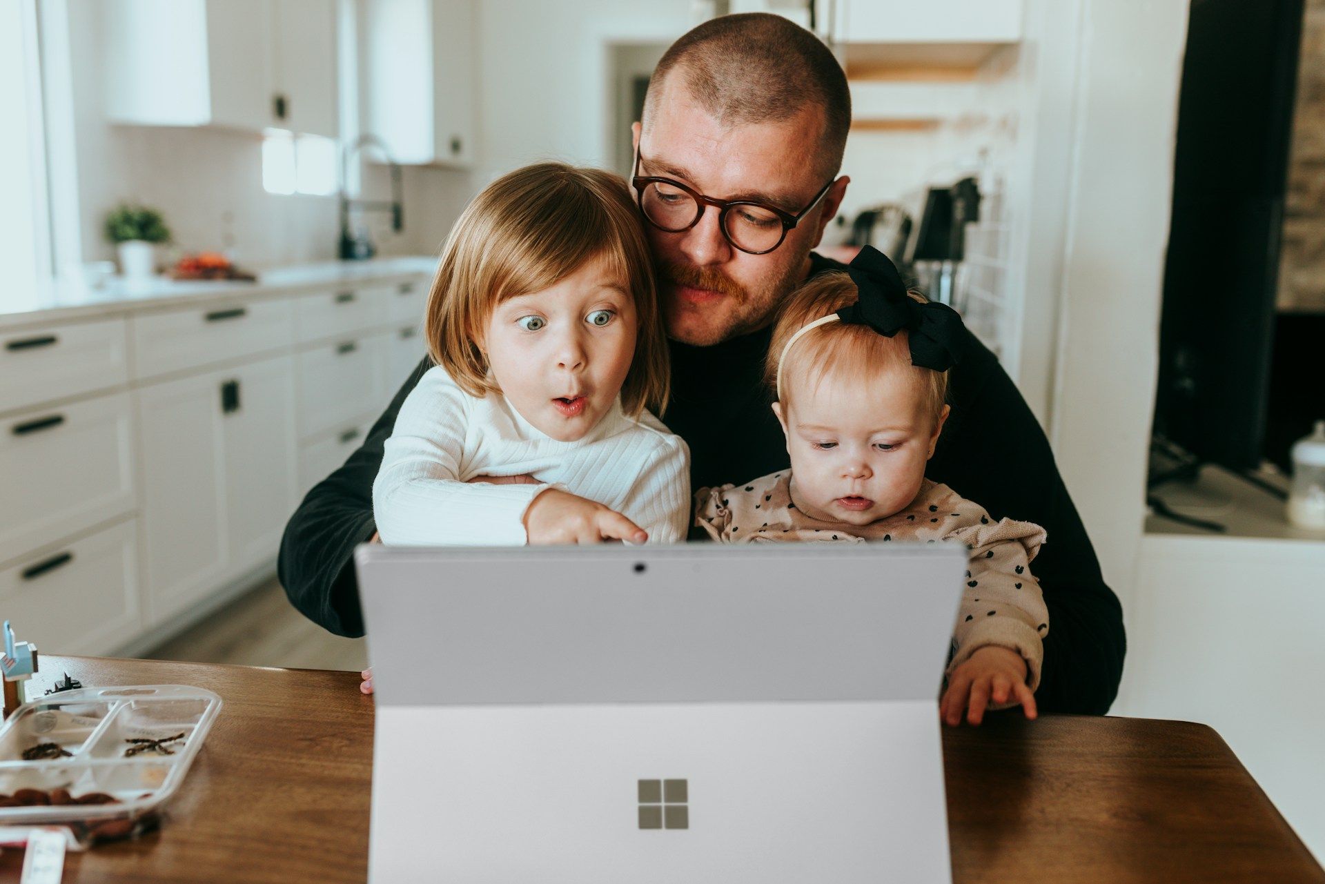 A dad using a tablet with his two children